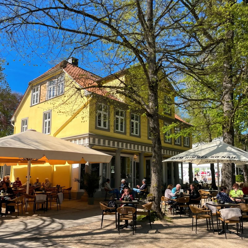 Außenansicht des Café am Kurpark in Bad Pyrmont mit Sonnenterrasse und Gästen