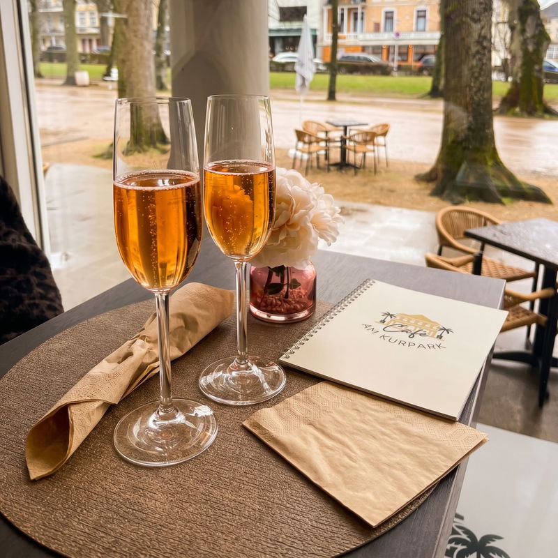 Zwei Gläser Sekt mit Blick auf den Kurpark im Café am Kurpark Bad Pyrmont