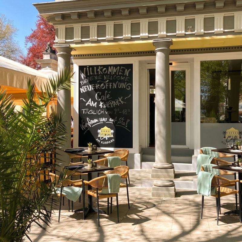 Willkommenstafel zur Neueröffnung des Café am Kurpark in Bad Pyrmont auf sonniger Terrasse