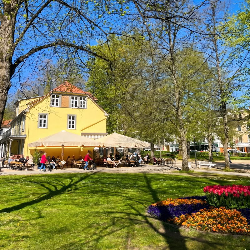 Café am Kurpark Bad Pyrmont mit Sonnenterrasse und Blumenbeeten im Frühling